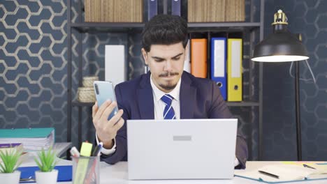 Businessman-working-in-office,-entering-information-from-phone-to-laptop.